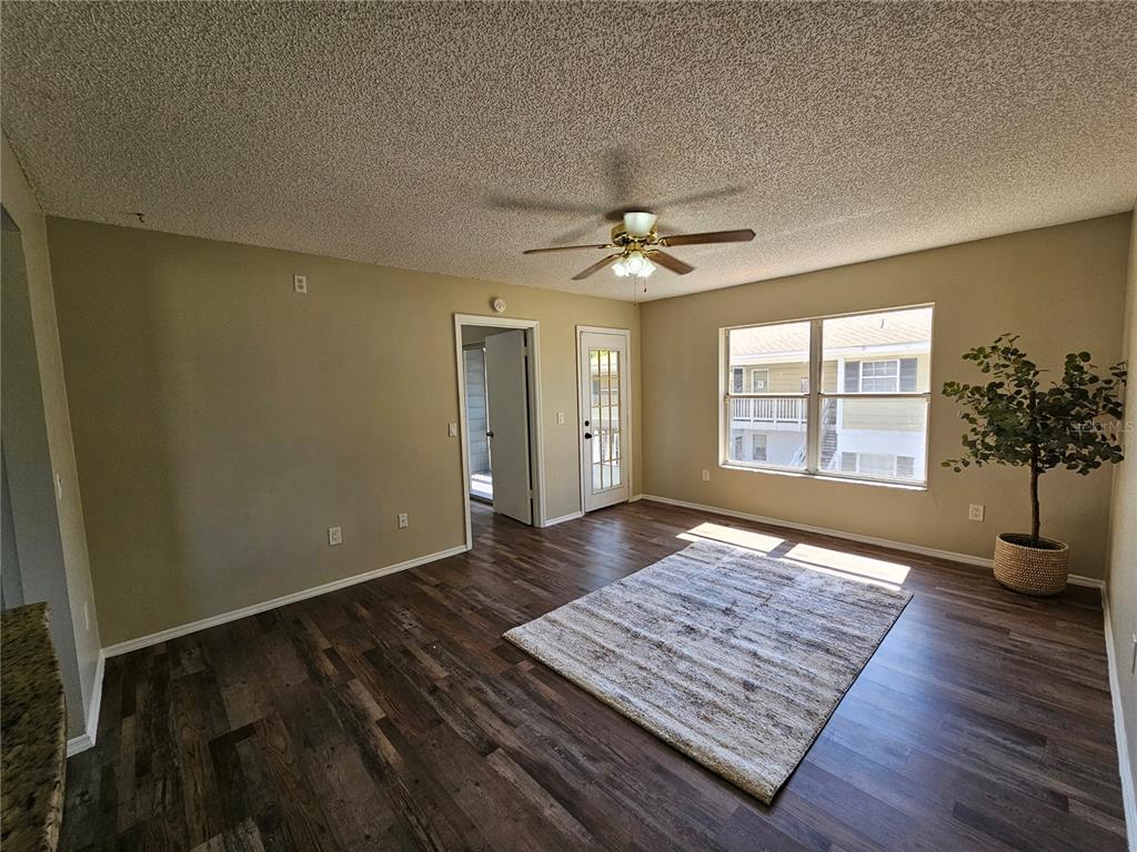 A living room features wood-look flooring, a ceiling fan, a rug, and a glass-paneled door — 8142 FAIRWAYS CIRCLE UNIT S204, OCALA, FL