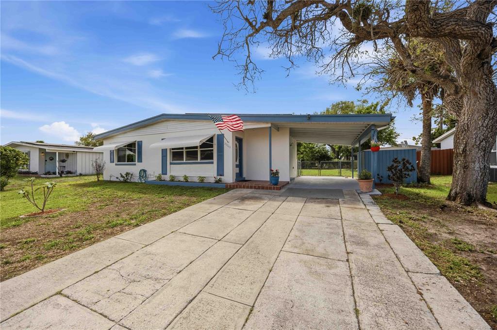 A single-story house with a concrete driveway, a carport, and a large tree in front — 22243 HERNANDO AVENUE, PORT CHARLOTTE, FL