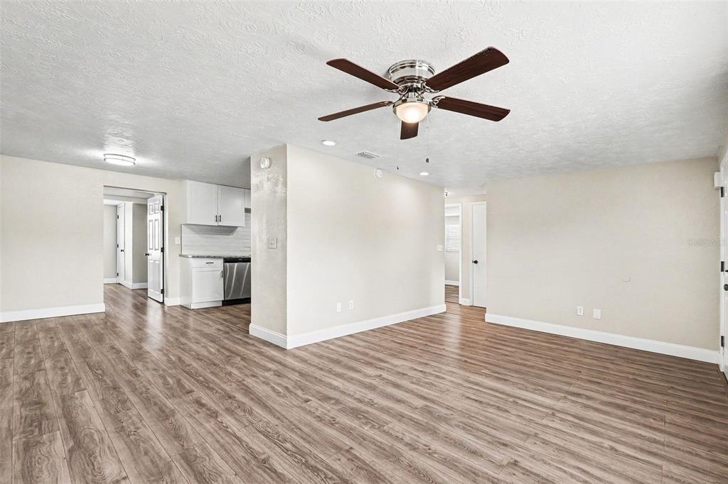 An open-concept living area with wood-look flooring, a ceiling fan, and an adjacent kitchen — 4113 KIBLER LANE, HOLIDAY, FL