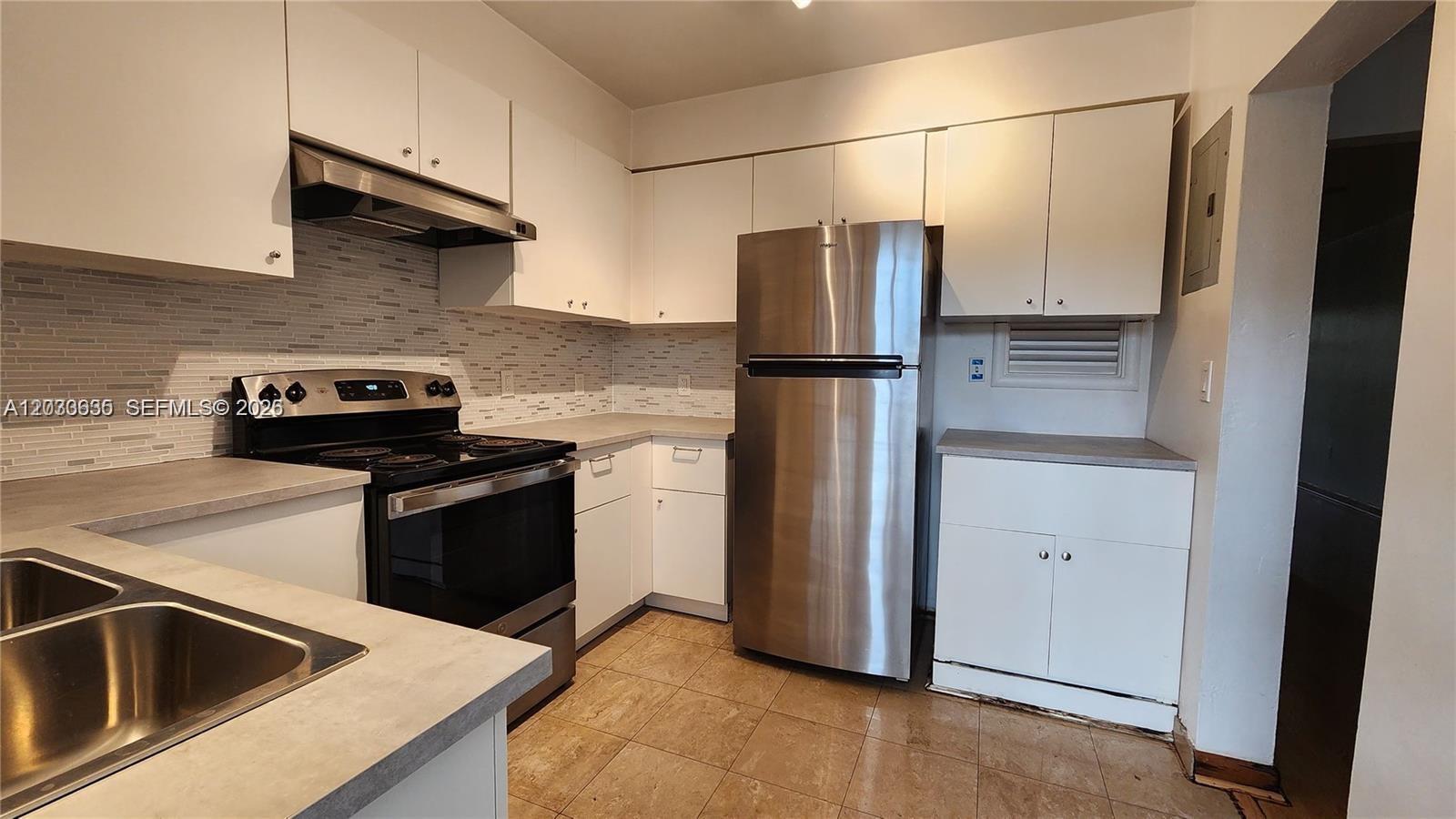 A kitchen features white cabinets, stainless steel appliances, a tiled backsplash, and light-colored countertops — 20 Park Dr # 4A, Bal Harbour FL 33154, BAL HARBOUR, FL