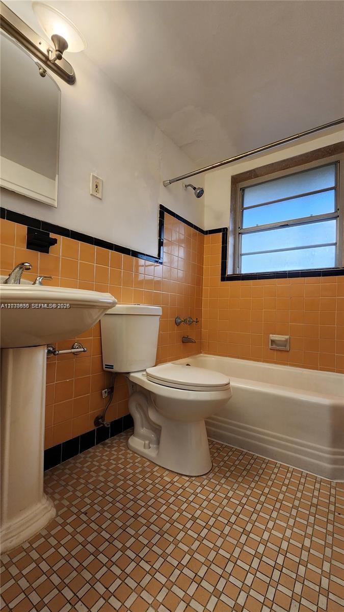 A bathroom features orange wall tiles, a pedestal sink, a toilet, and a bathtub — 20 Park Dr # 4A, Bal Harbour FL 33154, BAL HARBOUR, FL