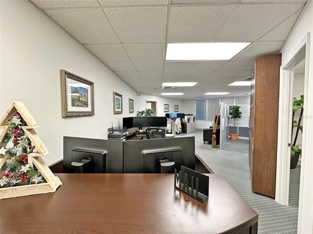 An office space features a wooden desk, computer monitors, and a drop ceiling — 7800 KINGSPOINTE PARKWAY UNIT 102, ORLANDO, FL