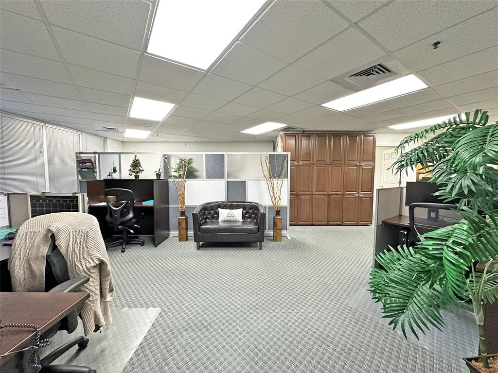 An office space features cubicle workstations, a central leather loveseat, and a large wooden cabinet — 7800 KINGSPOINTE PARKWAY UNIT 102, ORLANDO, FL