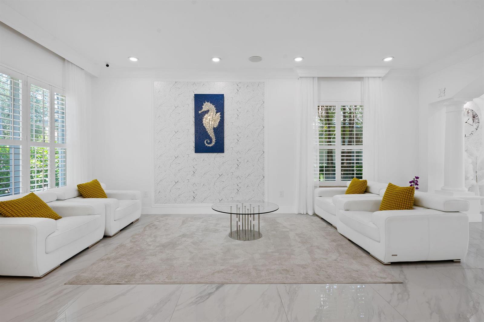 A bright living room features white sofas, a glass coffee table, and a seahorse artwork — 9559 Barletta Winds Point, Delray Beach FL 33446, DELRAY BEACH, FL