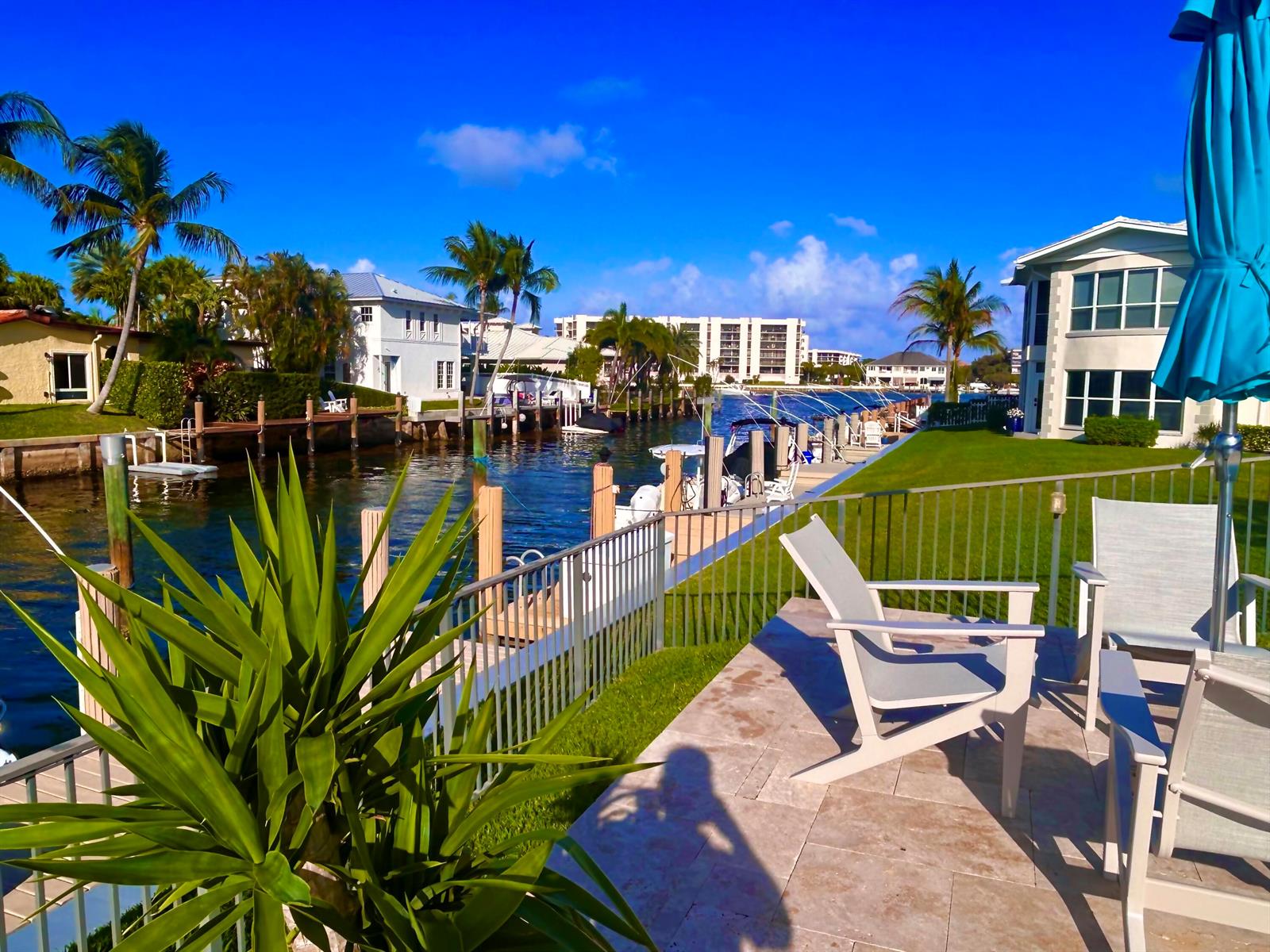 A patio with chairs overlooks a canal lined with houses, palm trees, and boat docks — 701 NE Harbour Terrace # 2140, Boca Raton FL 33431, BOCA RATON, FL