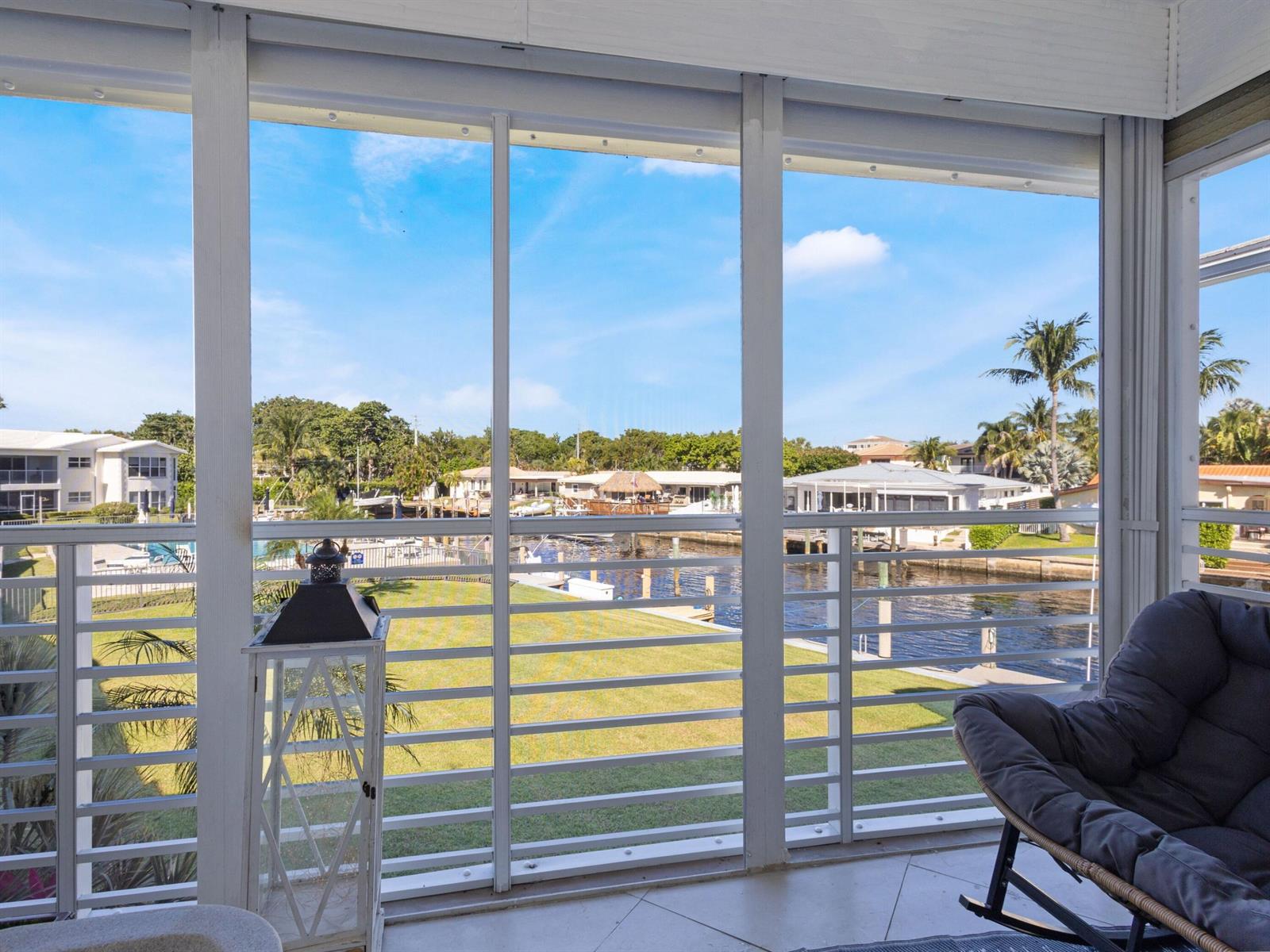 A screened-in porch overlooks a canal, green lawn, and residential waterfront properties — 701 NE Harbour Terrace # 2140, Boca Raton FL 33431, BOCA RATON, FL