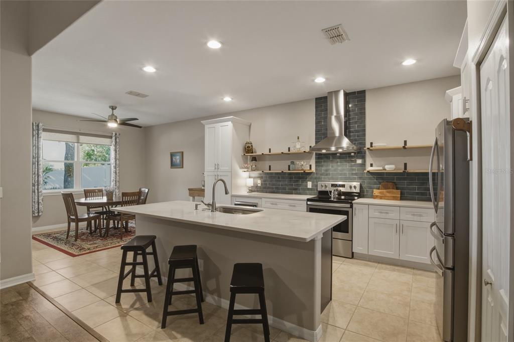 A kitchen with a central island, white cabinets, open shelving, and an adjacent dining area — 1893 SANDERLING DRIVE, CLERMONT, FL