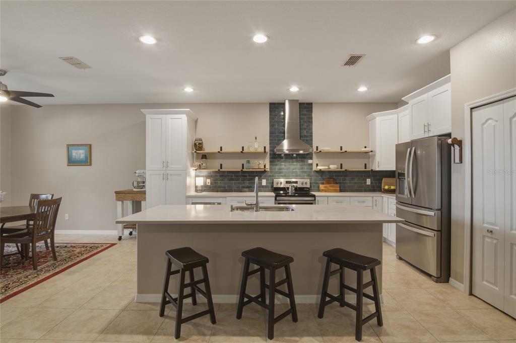 A kitchen with white cabinets, a central island, stainless steel appliances, and open shelving — 1893 SANDERLING DRIVE, CLERMONT, FL
