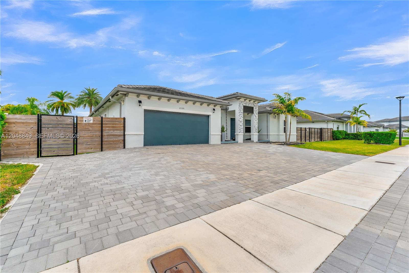 A single-story house with a paved driveway, a two-car garage, and a wooden side fence — 21100 SW 127th Pl, Miami FL 33177, MIAMI, FL