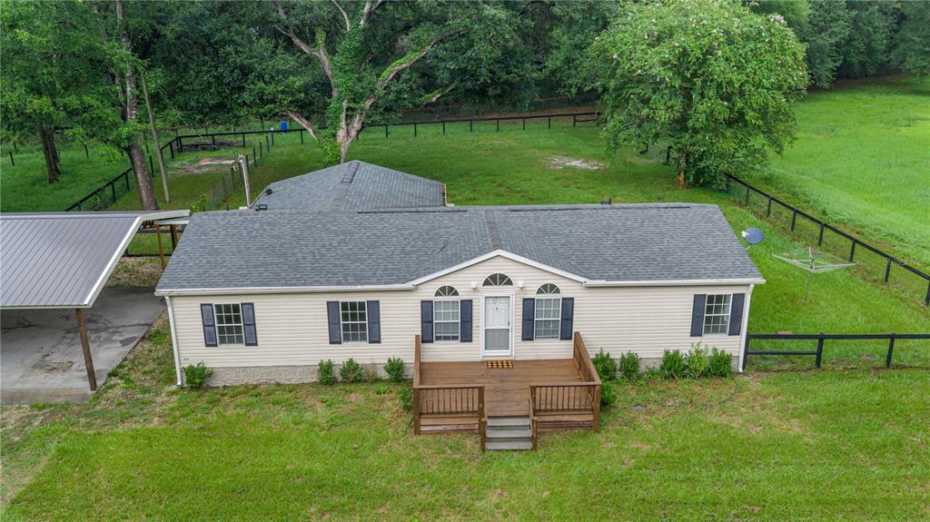 An aerial view of a single-story house with a wooden deck and a metal carport — 13250 NW 160TH AVENUE, MORRISTON, FL