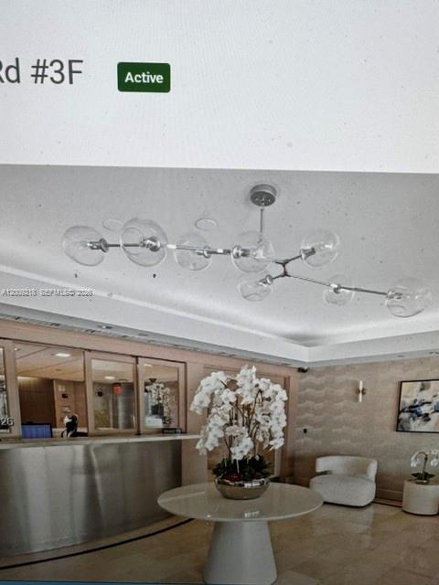 A modern lobby features a round table with orchids, a glass chandelier, and a reception desk — 200 SE 15th Rd, Miami FL 33129, MIAMI, FL