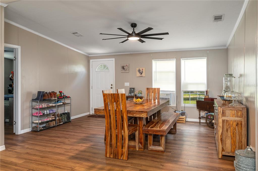 A dining room features wood-look flooring, a wooden table with chairs and a bench, and a fan — 15079 BRAHMA ROAD, POLK CITY, FL