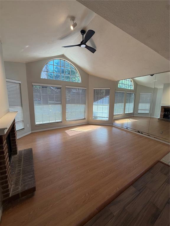 A living room features vaulted ceilings, a brick fireplace, wood-look flooring, and mirrored walls — 949 BIRD BAY COURT UNIT 101, LAKE MARY, FL