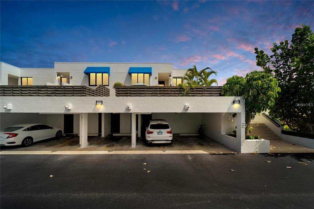 A white multi-story building features a ground-level covered parking area and second-story balconies — 829 BAYPORT WAY UNIT 829, LONGBOAT KEY, FL