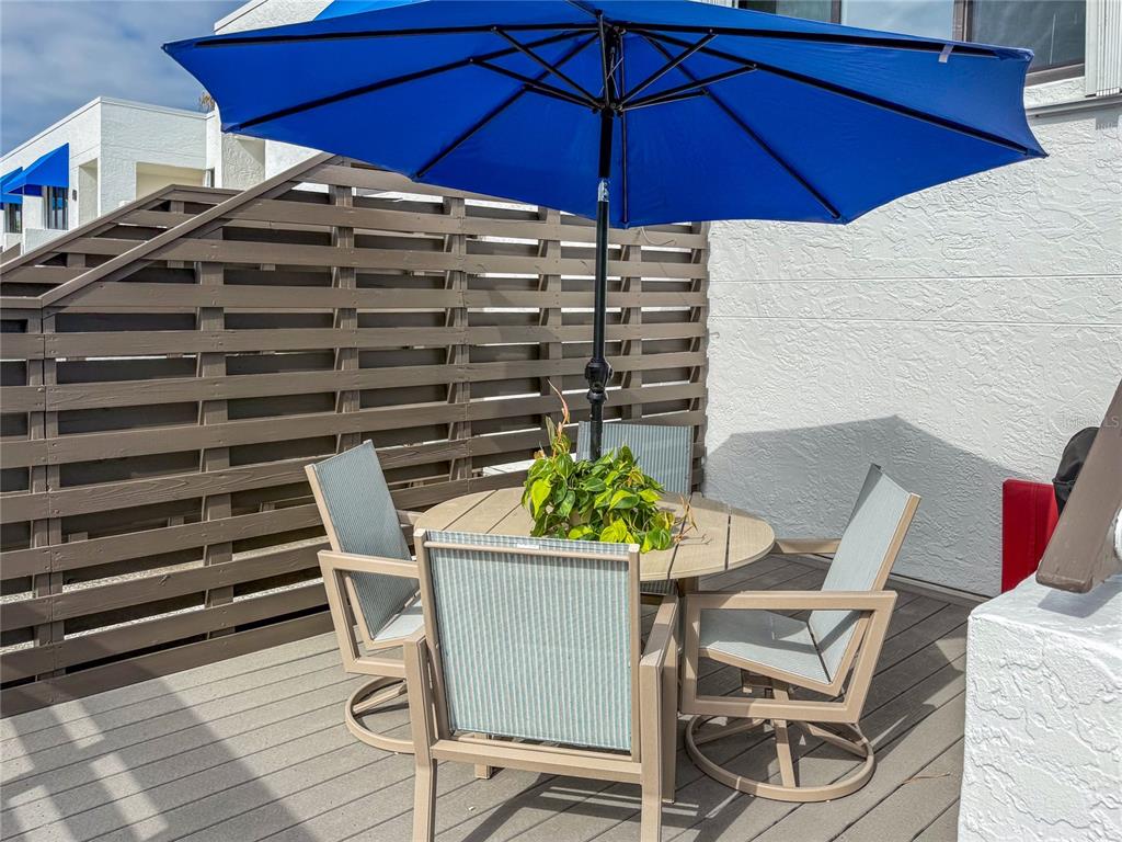 A patio features a round table with four chairs under a blue umbrella — 829 BAYPORT WAY UNIT 829, LONGBOAT KEY, FL
