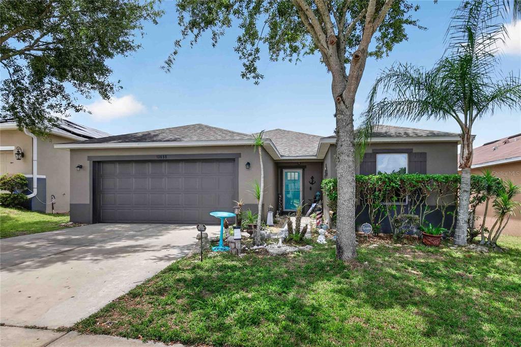 A single-story house with a gray garage, a teal front door, and a front yard — 13655 LARANJA ST, CLERMONT, FL