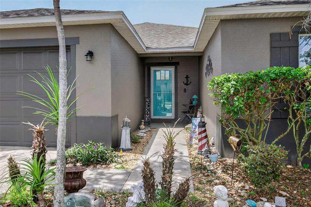 A house exterior features a light blue front door, a concrete walkway, and nautical decor — 13655 LARANJA ST, CLERMONT, FL