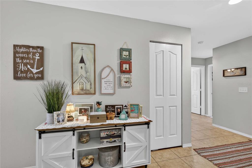 A white farmhouse-style console table sits against a wall decorated with framed art and photos — 13655 LARANJA ST, CLERMONT, FL