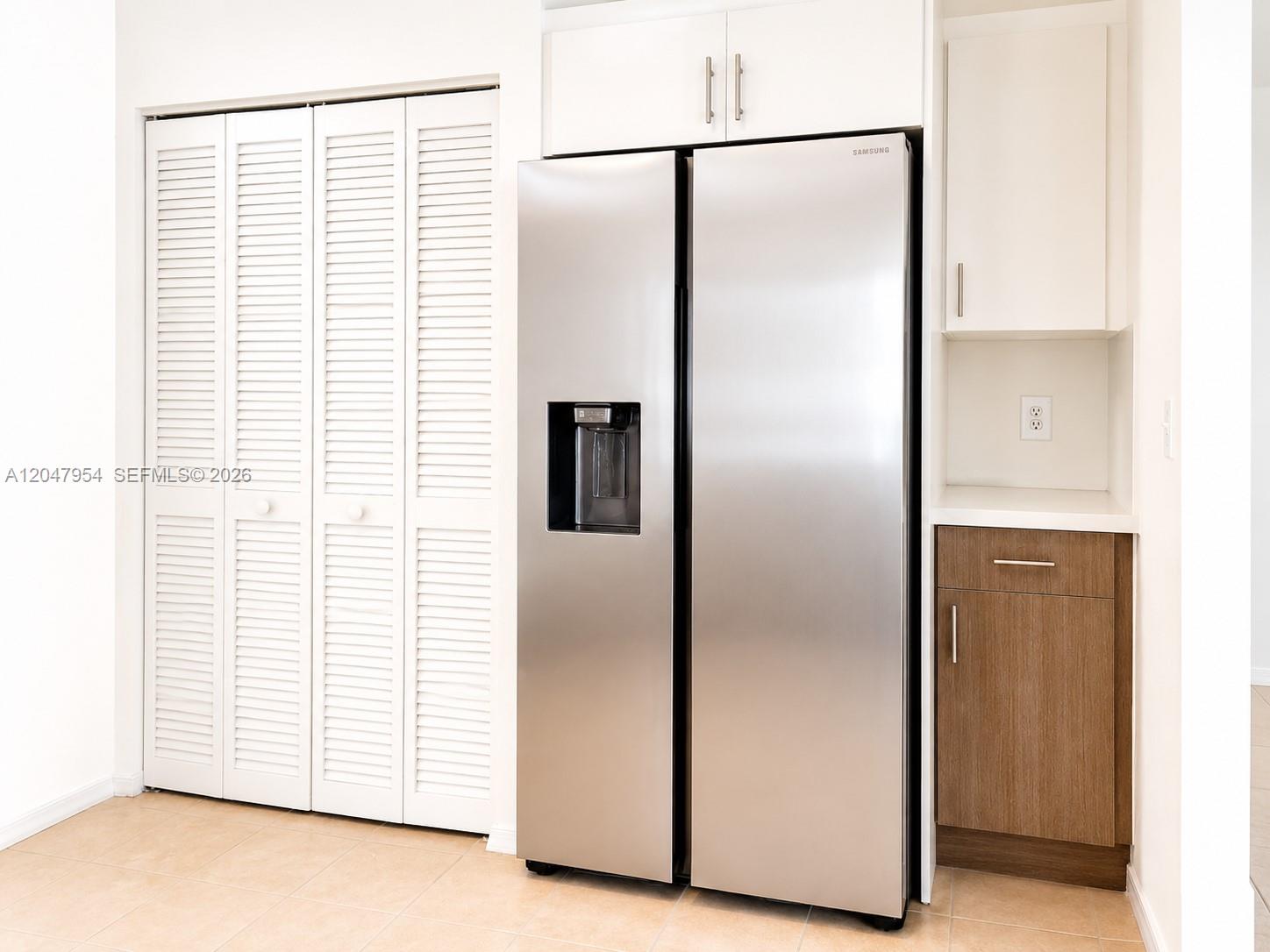 A stainless steel refrigerator is positioned between white louvered closet doors and wood-toned cabinetry — 3 Whitehead Cir # 3, Weston FL 33326, WESTON, FL