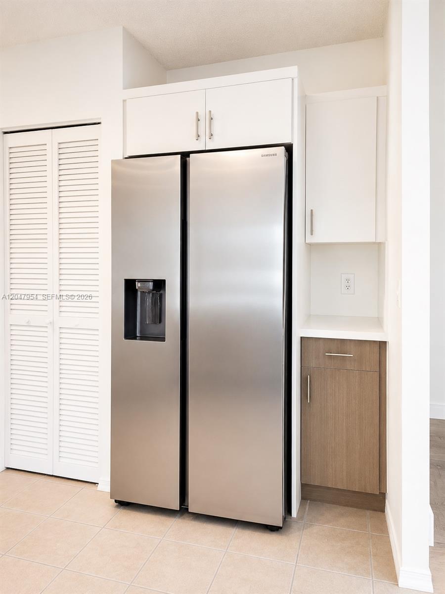 A stainless steel refrigerator sits next to a small cabinet and counter in a kitchen — 3 Whitehead Cir # 3, Weston FL 33326, WESTON, FL