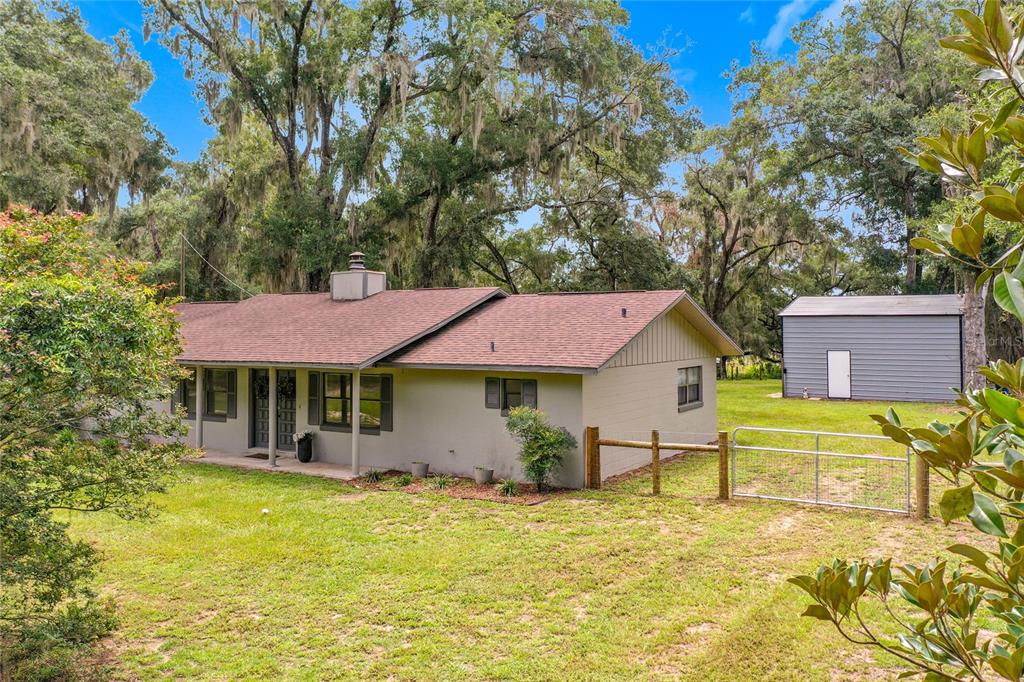 A single-story house with a brown roof and a detached metal shed in the yard — 26586 SE HIGHWAY 42, UMATILLA, FL
