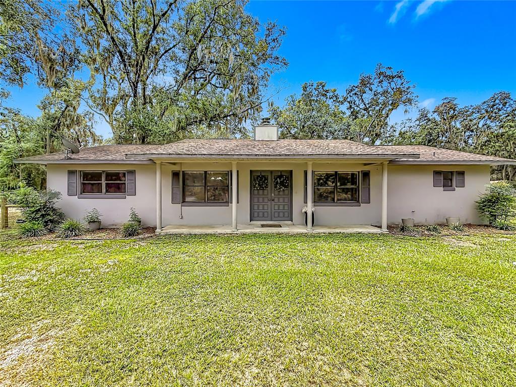 A single-story house with a covered front porch, gray exterior, and a large grassy lawn — 26586 SE HIGHWAY 42, UMATILLA, FL