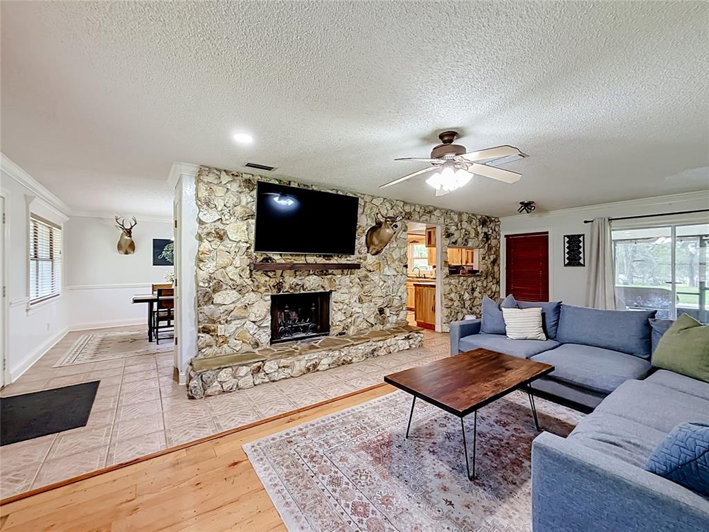 A living room features a stone fireplace, a blue sectional sofa, and hardwood flooring — 26586 SE HIGHWAY 42, UMATILLA, FL