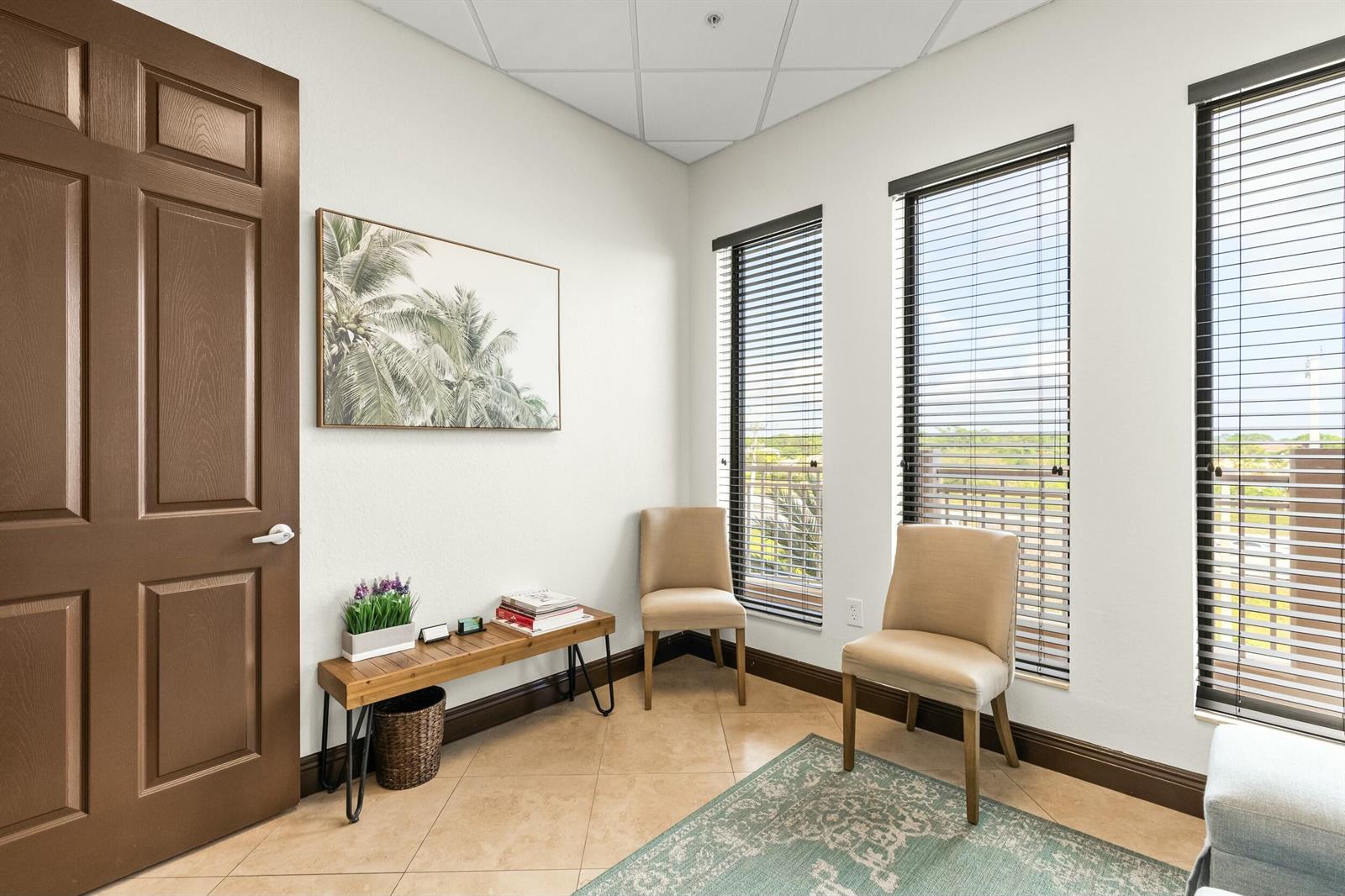 A small room features tile flooring, two beige chairs, a wooden bench, and three windows — 3319 S State Rd 7, Wellington FL 33449, WELLINGTON, FL