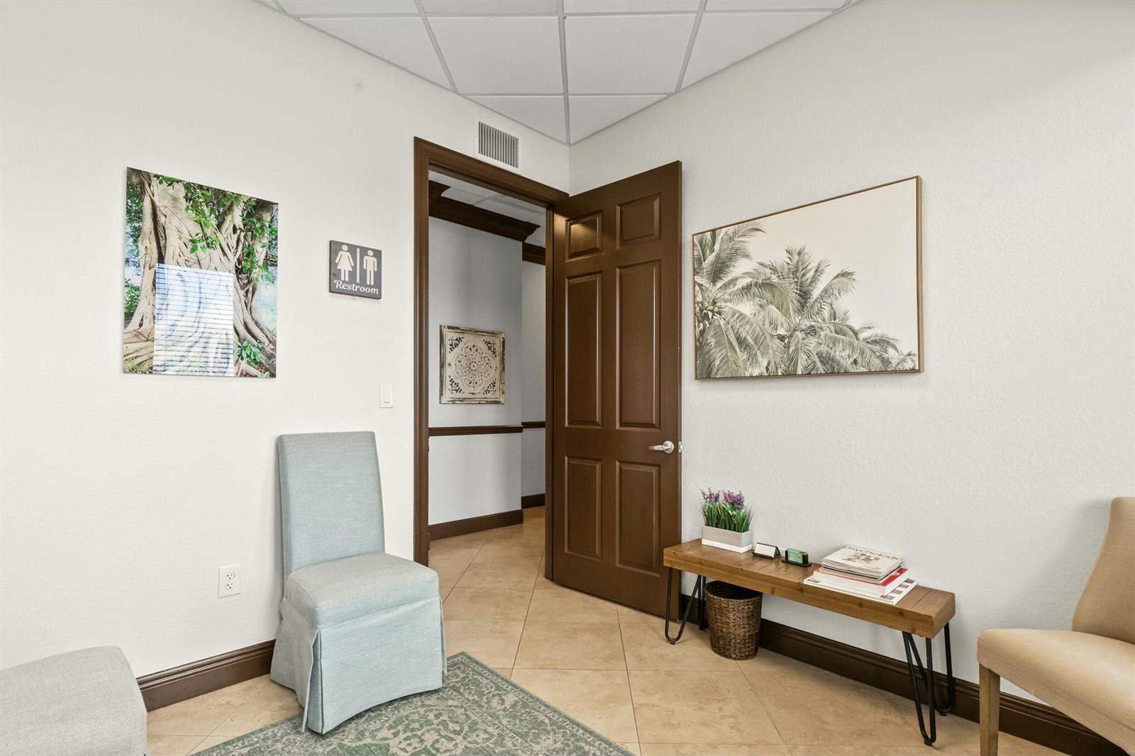 A waiting room features tile floors, a brown door, two chairs, and wall art — 3319 S State Rd 7, Wellington FL 33449, WELLINGTON, FL