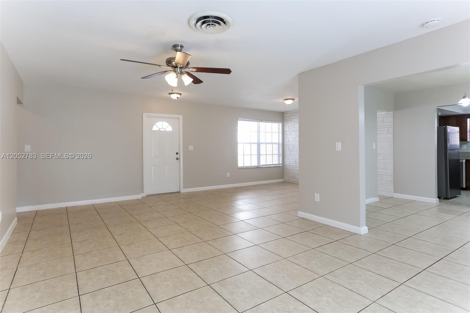 A living room with beige tile flooring, a ceiling fan, and an adjacent kitchen area — 2230 NW 42nd Ave, Lauderhill FL 33313, LAUDERHILL, FL