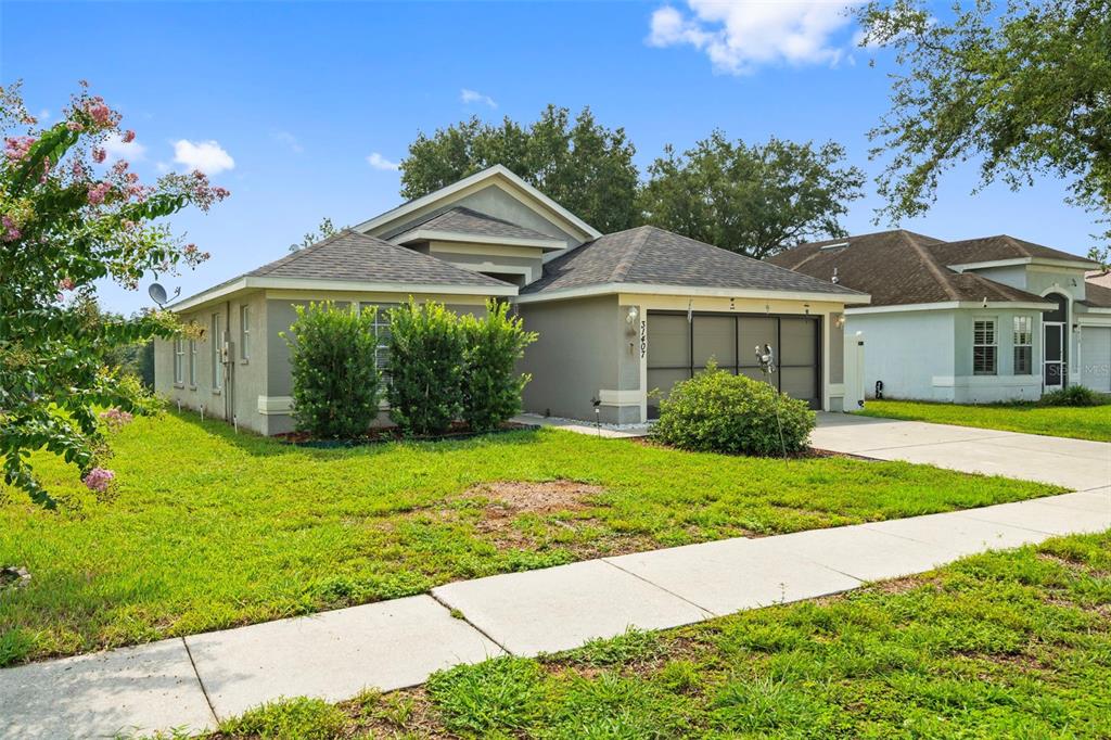 A single-story house with a gray exterior, a two-car garage, and a front lawn — 31407 SATINLEAF RUN, BROOKSVILLE, FL
