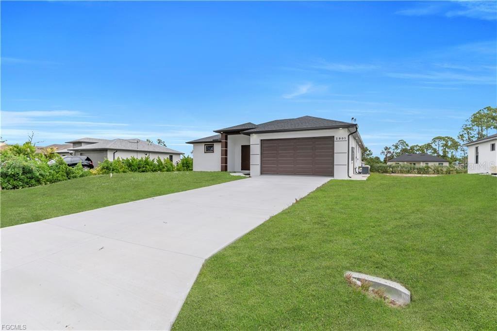 A single-story house with a white exterior, dark garage door, and a concrete driveway — 2901 VILLA AVENUE S, LEHIGH ACRES, FL
