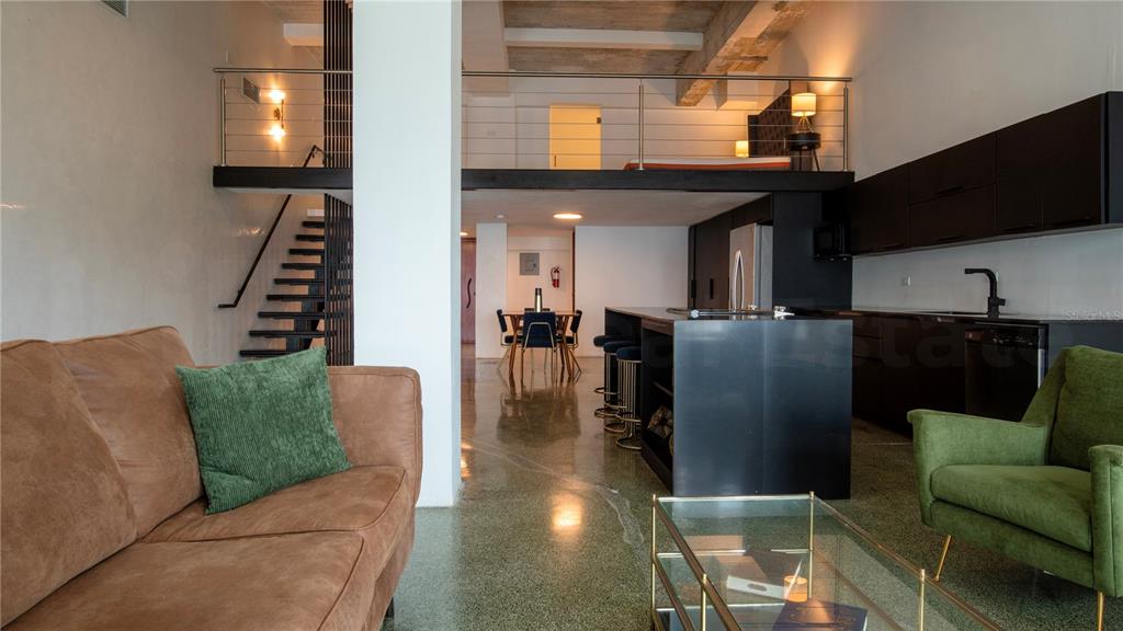A modern open-concept living area features a lofted bedroom, concrete floors, and a black kitchen — 203 RECINTO SUR UNIT 5, OLD SAN JUAN, PR