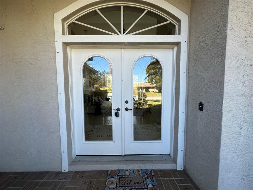 A white double front door with arched glass panels sits under a semi-circular transom window — 4580 CRYSTAL ROAD, VENICE, FL