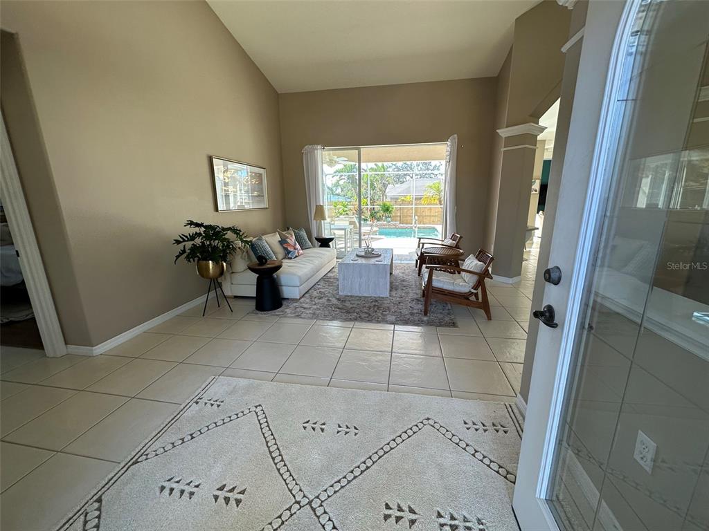 A living room with tile floors, a rug, and a sliding door leading to a pool — 4580 CRYSTAL ROAD, VENICE, FL
