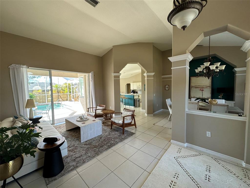 A living room with tile floors, a sliding glass door to a pool, and an adjacent kitchen — 4580 CRYSTAL ROAD, VENICE, FL
