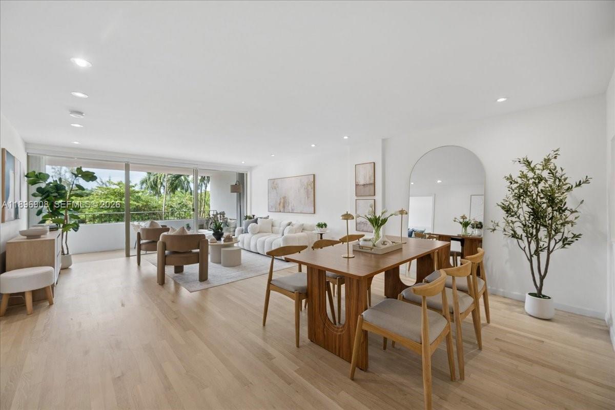 A bright, open-concept living and dining area features light wood floors and a balcony view — 155 Ocean Lane Dr # 302, Key Biscayne FL 33149, KEY BISCAYNE, FL