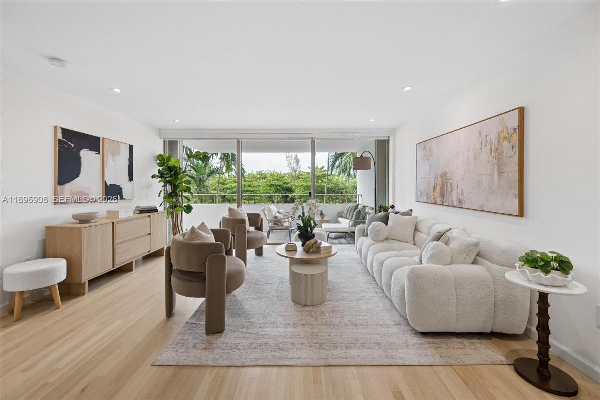 A bright living room features a white sofa, two armchairs, a wooden sideboard, and floor-to-ceiling windows — 155 Ocean Lane Dr # 302, Key Biscayne FL 33149, KEY BISCAYNE, FL