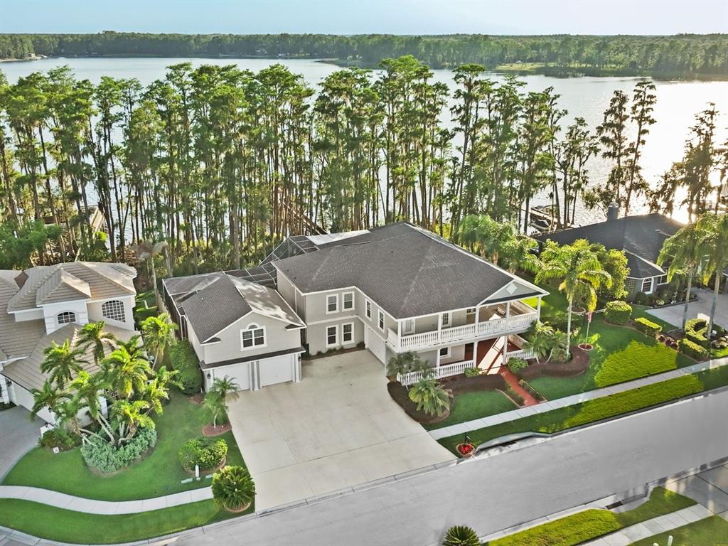 An aerial view shows a two-story house with a garage, balcony, and lakefront backyard — 21019 MARSH HAWK DRIVE, LAND O LAKES, FL