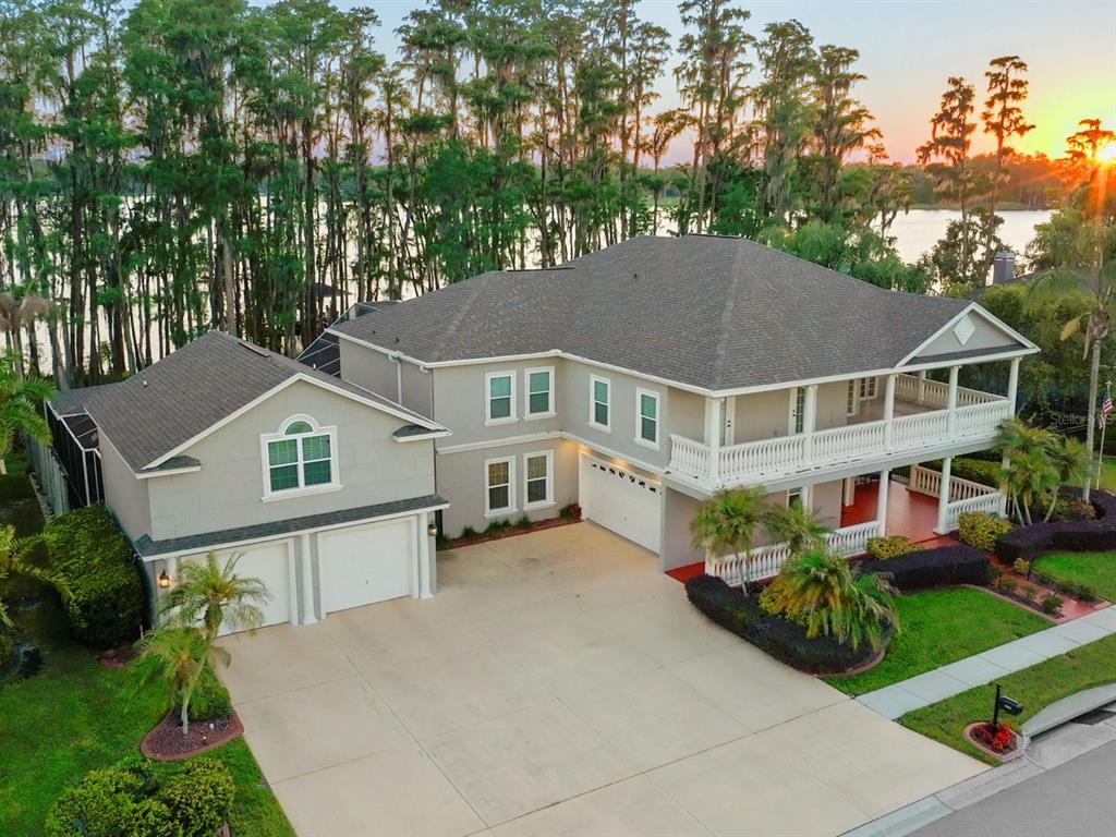 An aerial view of a two-story house with a large driveway and a lakefront backyard — 21019 MARSH HAWK DRIVE, LAND O LAKES, FL