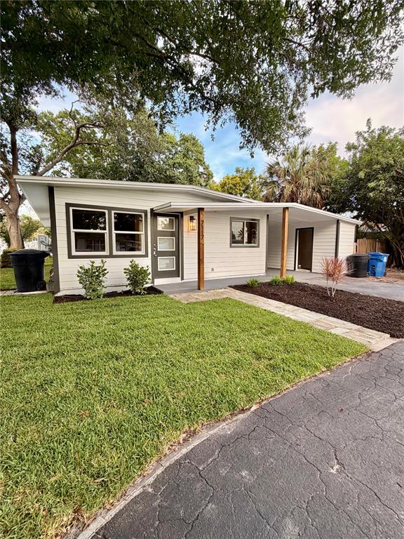 A single-story house with white siding, a front porch, and a paved driveway — 7117 15TH STREET N, ST PETERSBURG, FL