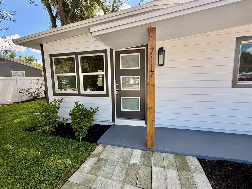 A white house exterior features a dark gray front door with three glass panels — 7117 15TH STREET N, ST PETERSBURG, FL