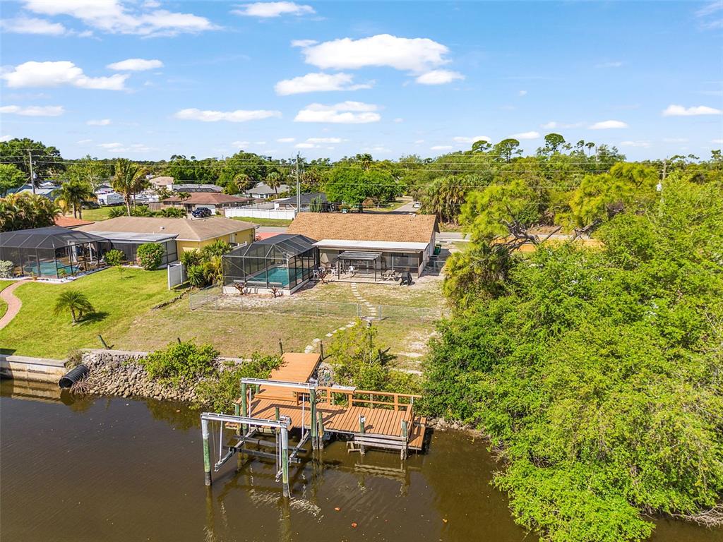 An aerial view of a waterfront house with a pool enclosure and a wooden dock — 2368 PELLAM BOULEVARD, PORT CHARLOTTE, FL