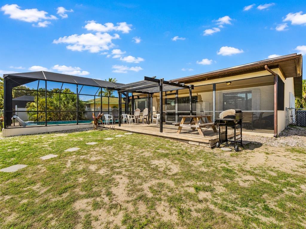 A backyard features a wooden deck, a screened-in pool enclosure, and a picnic table — 2368 PELLAM BOULEVARD, PORT CHARLOTTE, FL