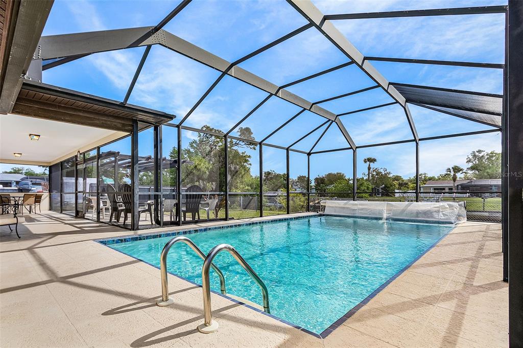 A screened-in swimming pool with a metal frame enclosure and a covered patio area — 2368 PELLAM BOULEVARD, PORT CHARLOTTE, FL
