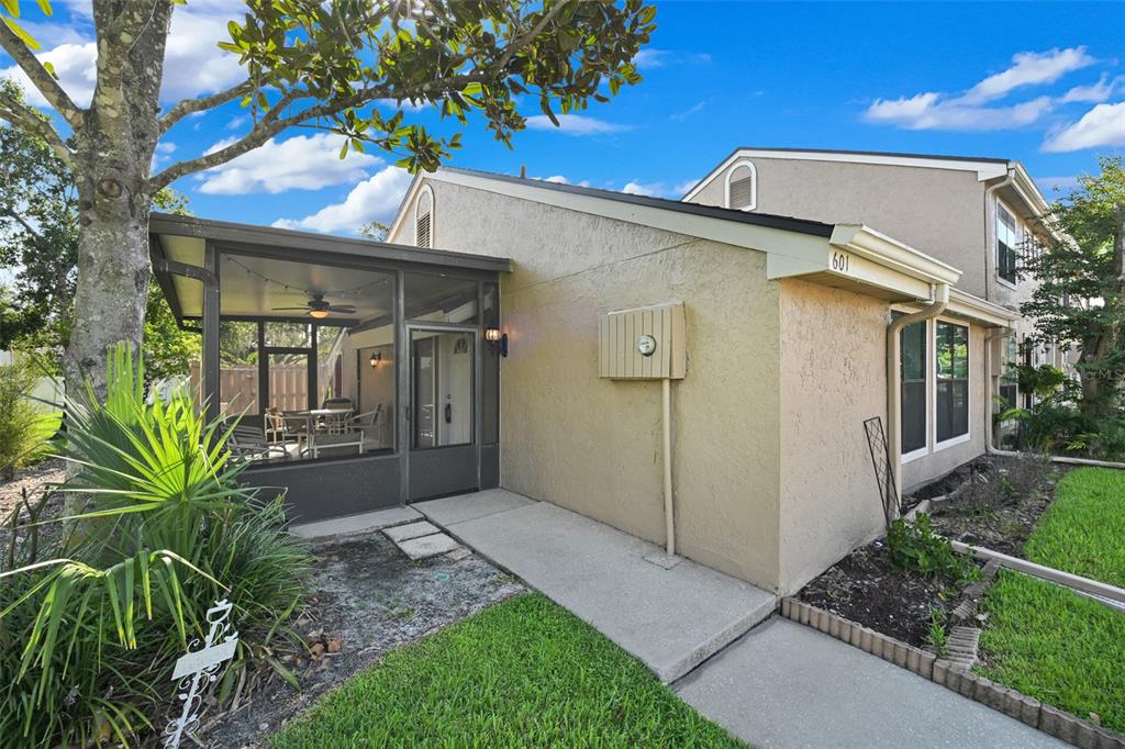 The exterior of a tan townhouse features a screened-in porch and a concrete walkway — 601 CASA PARK COURT K COURT UNIT K, WINTER SPRINGS, FL