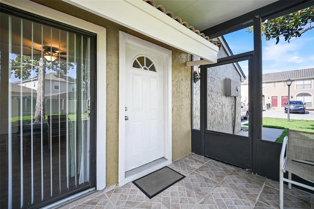 A white front door opens onto a tiled, screened-in porch with a sliding glass door — 601 CASA PARK COURT K COURT UNIT K, WINTER SPRINGS, FL