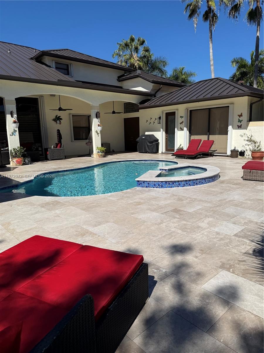 A backyard patio features a swimming pool, a raised hot tub, and red lounge chairs — 18610 SW 39th Ct, Miramar FL 33029, MIRAMAR, FL