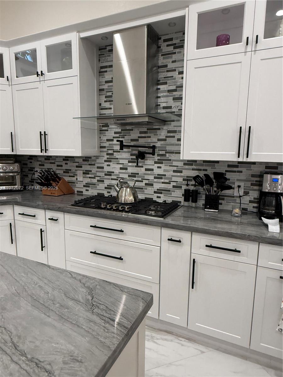 A kitchen features white cabinets, gray marble countertops, a mosaic tile backsplash, and stainless steel appliances — 18610 SW 39th Ct, Miramar FL 33029, MIRAMAR, FL