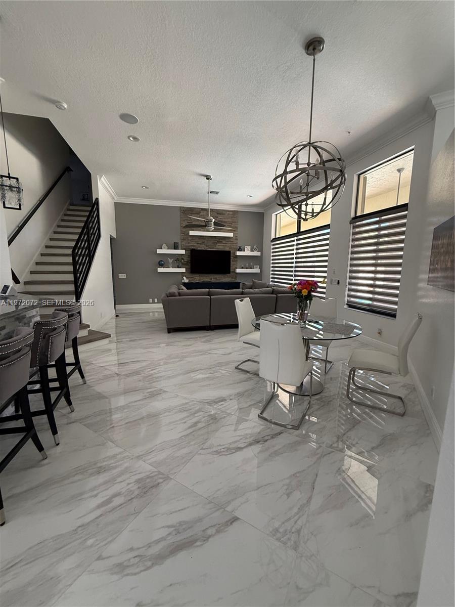 A modern open-concept living and dining area features white marble floors and a staircase — 18610 SW 39th Ct, Miramar FL 33029, MIRAMAR, FL